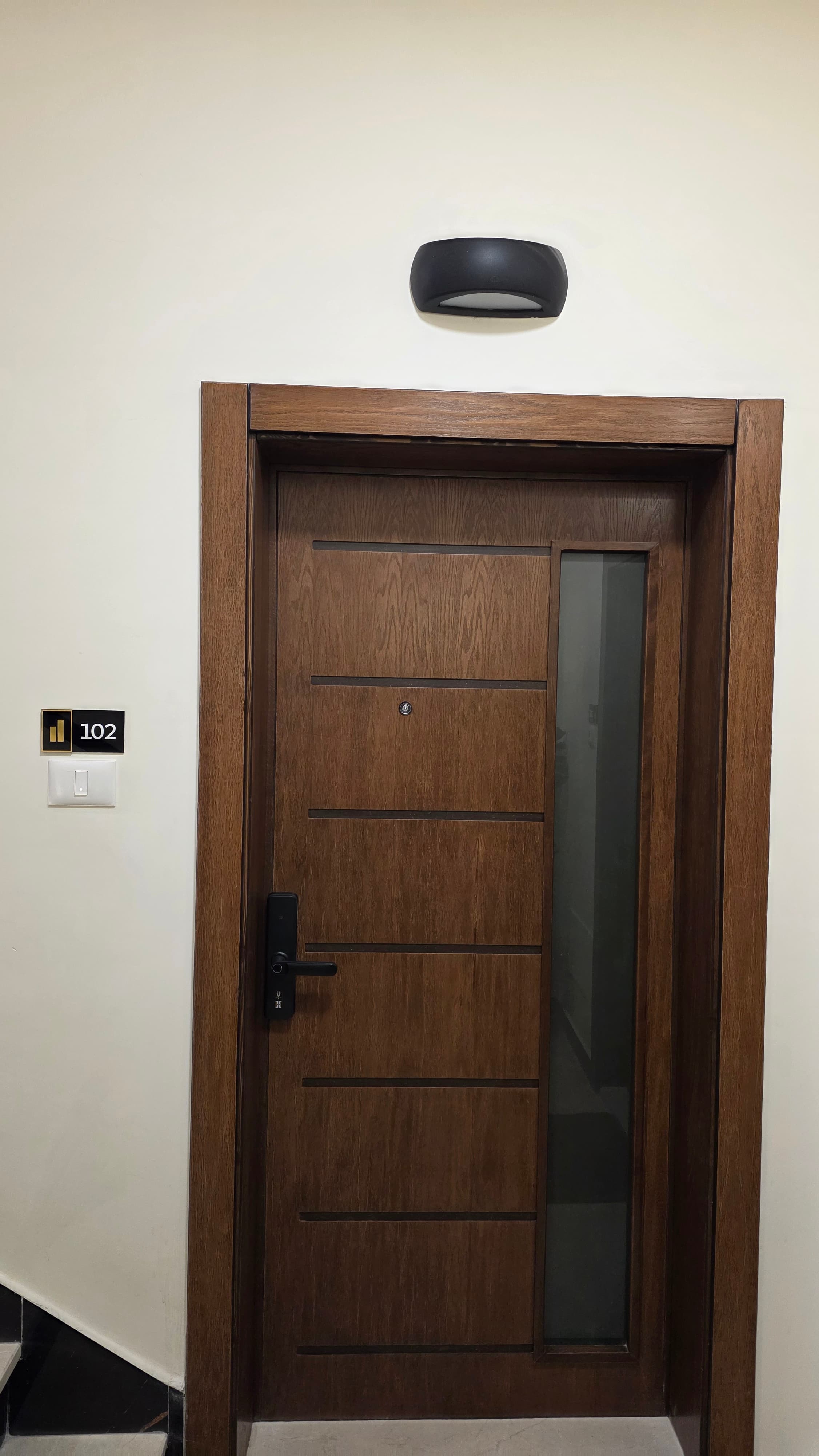 Walnut security door of Residence 102 with smart digital lock and branded gold plaque