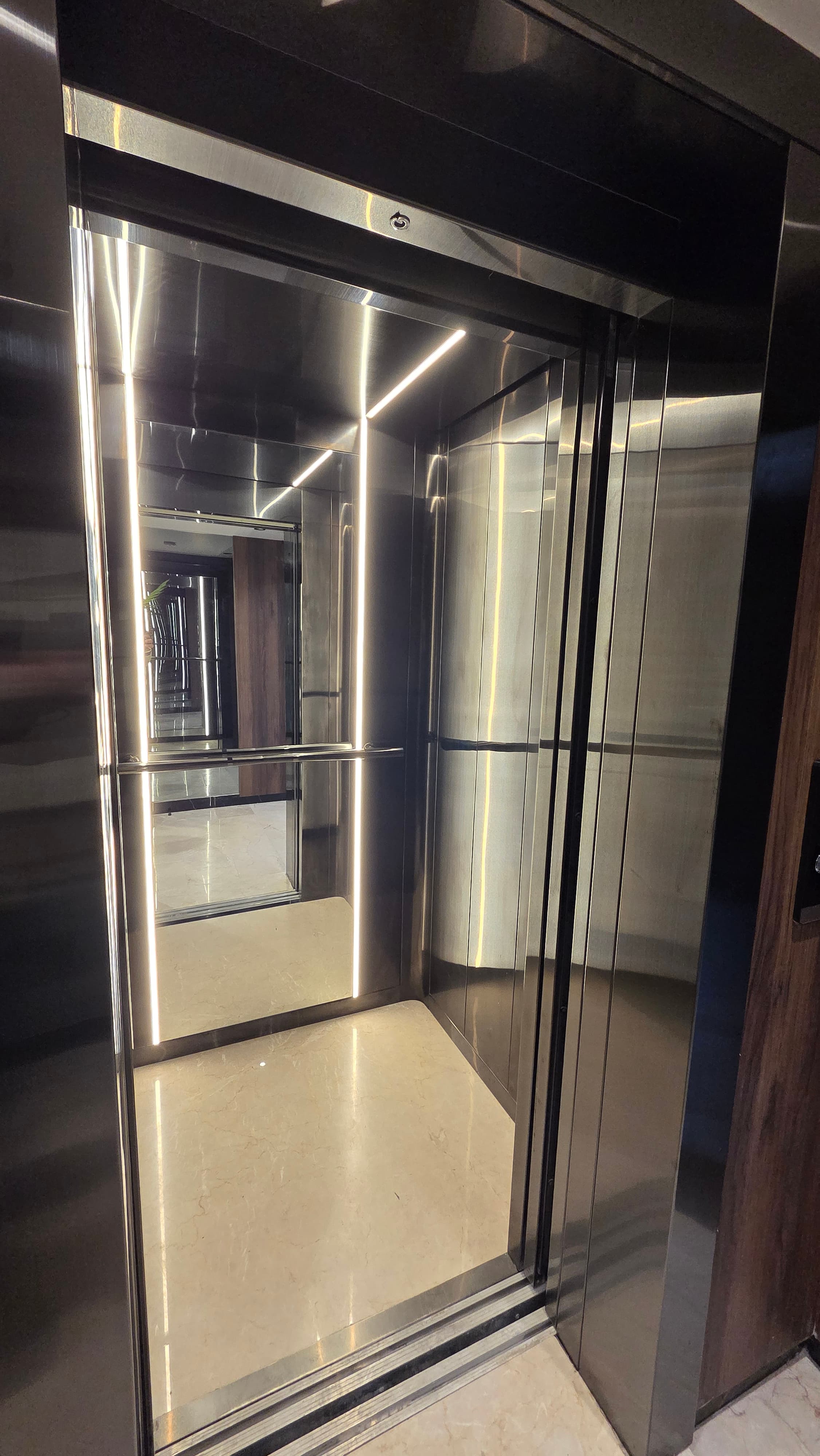 Elevator interior with stainless steel finish, LED strip lighting, and marble floor